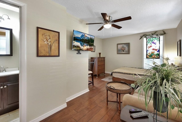 bedroom with a textured ceiling, wood-type flooring, a ceiling fan, and baseboards