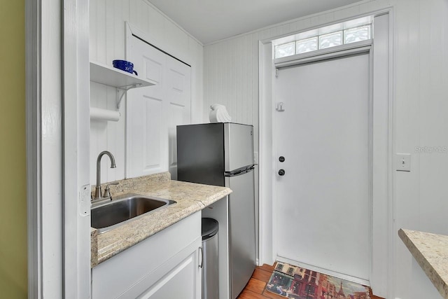 kitchen featuring light stone counters, a sink, white cabinetry, freestanding refrigerator, and open shelves