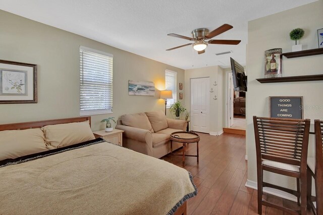 bedroom featuring a ceiling fan, wood-type flooring, visible vents, and baseboards