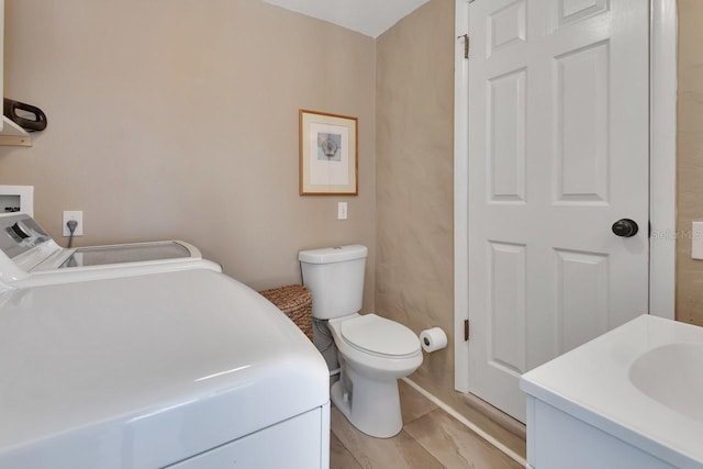 bathroom with washer and clothes dryer, toilet, and vanity