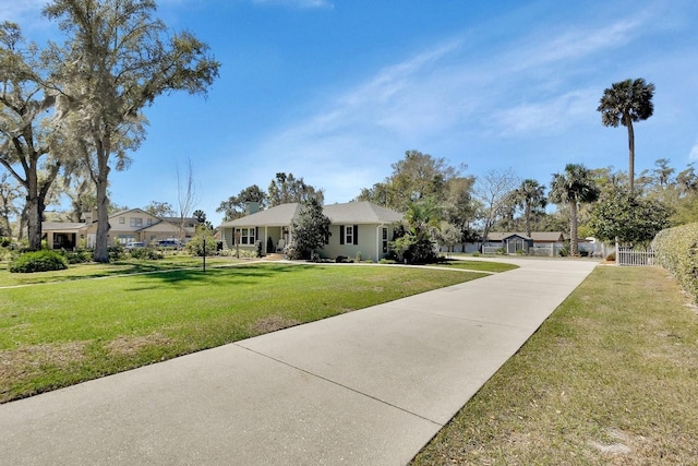 view of front facade with driveway, a front lawn, and fence