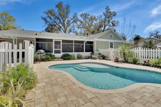 view of pool with a patio area, fence, a sunroom, and a fenced in pool