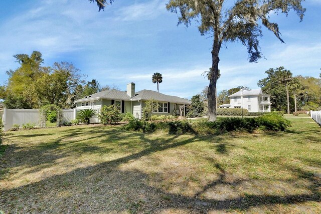 exterior space with a chimney, fence, and a front yard