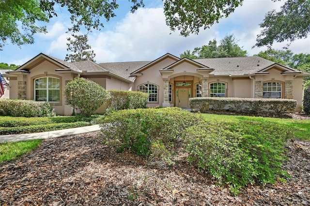 ranch-style home with stone siding, a shingled roof, and stucco siding