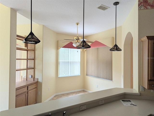 interior space with ceiling fan, decorative light fixtures, arched walkways, and visible vents