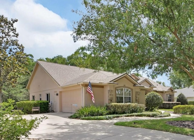 ranch-style house with concrete driveway, an attached garage, stucco siding, and a shingled roof