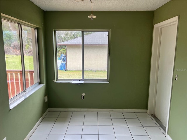 unfurnished room with a healthy amount of sunlight, a textured ceiling, and light tile patterned flooring