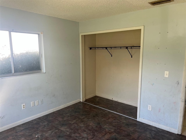 unfurnished bedroom featuring a closet, visible vents, a textured ceiling, and baseboards