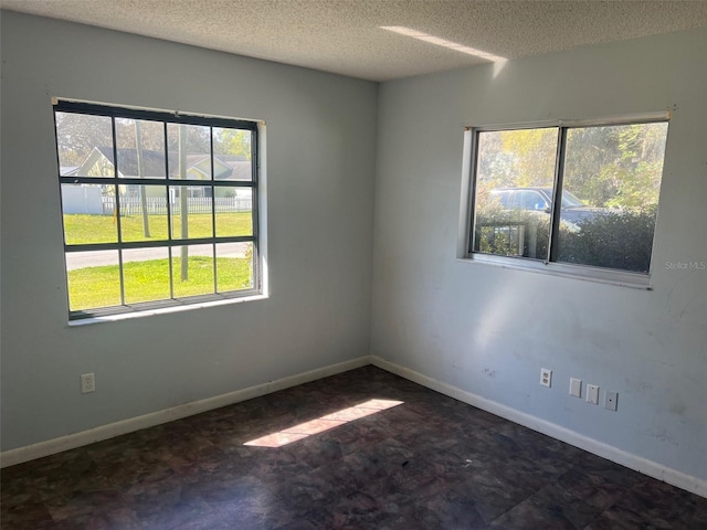 spare room with baseboards and a textured ceiling