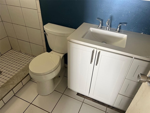 bathroom featuring tile patterned flooring, a tile shower, vanity, and toilet