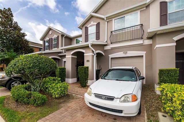 view of front of property featuring a garage, a balcony, and stucco siding