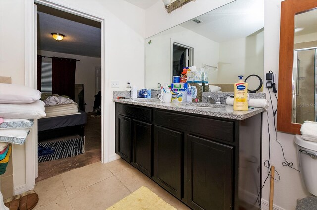 bathroom with double vanity, visible vents, ensuite bathroom, a sink, and tile patterned flooring