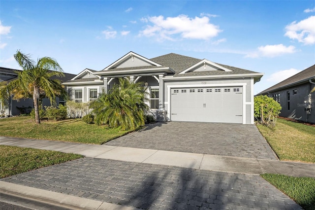 view of front facade with decorative driveway, an attached garage, a front lawn, and stucco siding