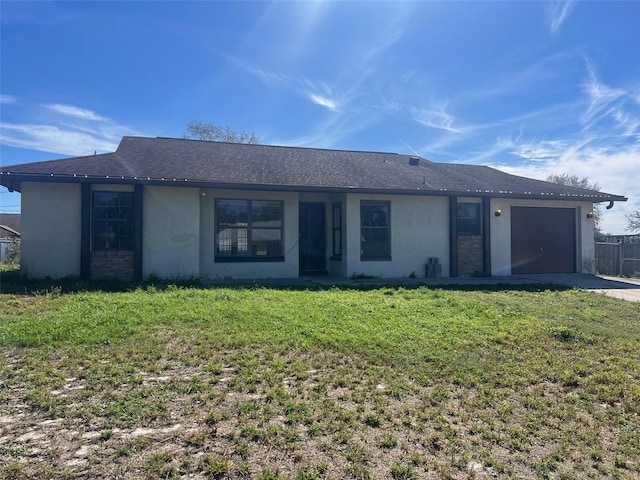 ranch-style home with an attached garage, driveway, a front yard, and stucco siding