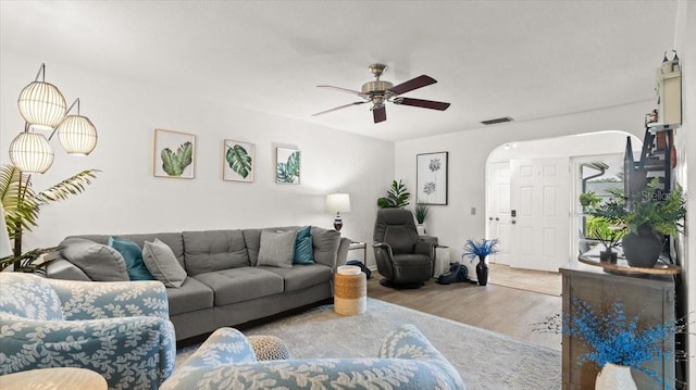 living area featuring ceiling fan, visible vents, arched walkways, and wood finished floors