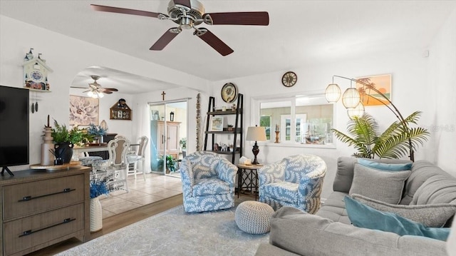 living room featuring arched walkways, wood finished floors, and a ceiling fan