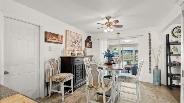 dining space featuring light tile patterned floors, a ceiling fan, and baseboards