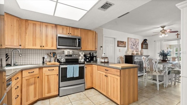 kitchen with visible vents, appliances with stainless steel finishes, light tile patterned flooring, a sink, and a peninsula