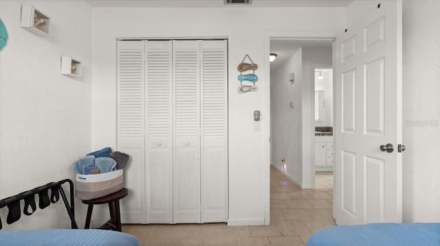 bedroom featuring light tile patterned floors, baseboards, visible vents, and a closet