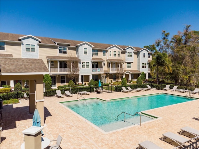 community pool featuring a patio, fence, and a residential view