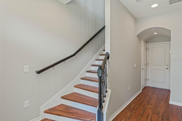 stairway featuring arched walkways, recessed lighting, wood finished floors, visible vents, and baseboards