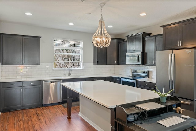 kitchen featuring dark wood finished floors, a breakfast bar area, appliances with stainless steel finishes, light countertops, and a sink