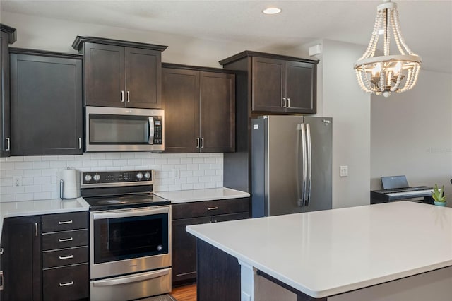 kitchen featuring stainless steel appliances, light countertops, dark brown cabinetry, and decorative backsplash