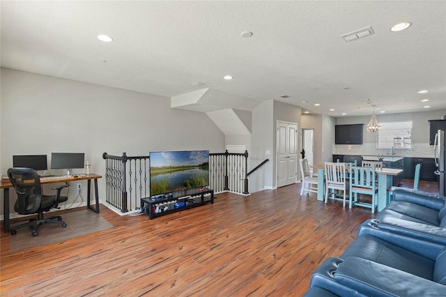 living area featuring baseboards, wood finished floors, visible vents, and recessed lighting