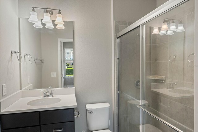 bathroom featuring toilet, a shower stall, and vanity