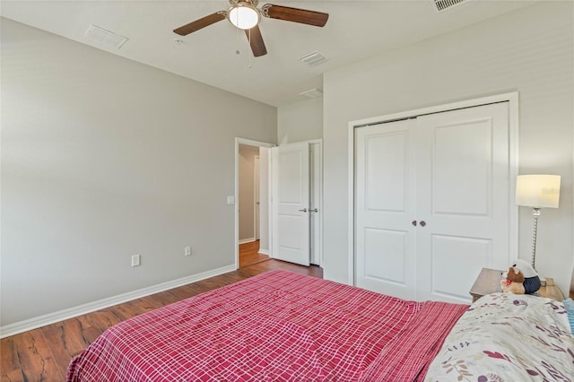 bedroom featuring ceiling fan, wood finished floors, visible vents, baseboards, and a closet