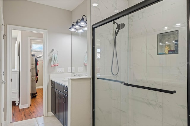 full bathroom with a spacious closet, a stall shower, vanity, and baseboards