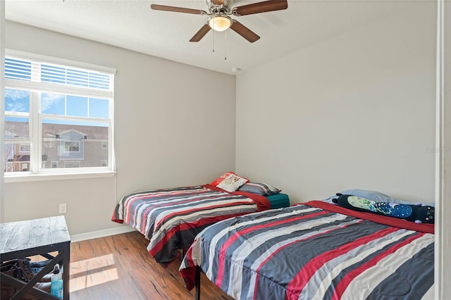 bedroom with ceiling fan, baseboards, and wood finished floors