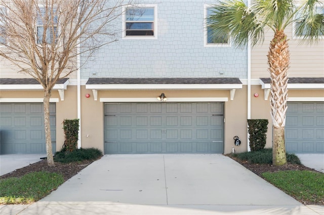 view of front of home with a garage, a shingled roof, concrete driveway, and stucco siding