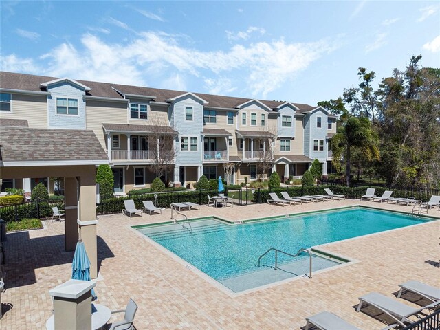 community pool featuring a patio area, fence, and a residential view