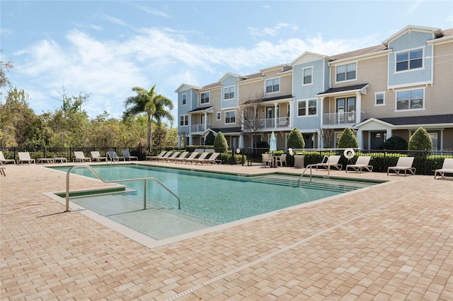 community pool with a residential view, a patio area, and fence