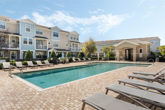 pool with a residential view, a patio area, and fence