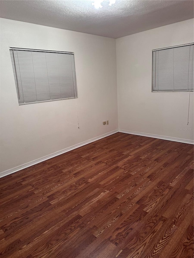 unfurnished room with visible vents, baseboards, dark wood finished floors, and a textured ceiling