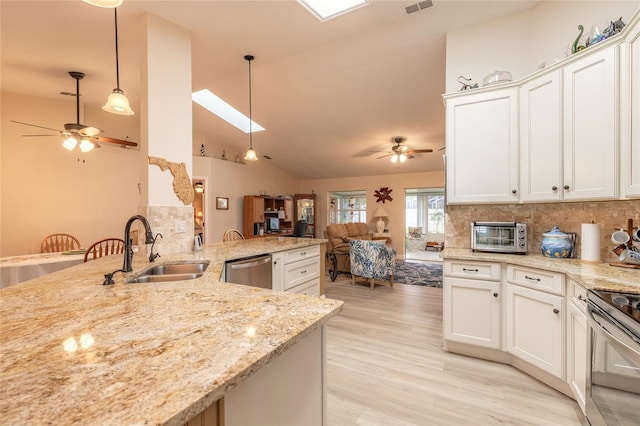 kitchen with backsplash, ceiling fan, open floor plan, stainless steel appliances, and a sink