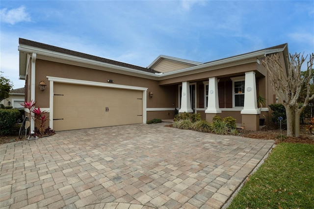 single story home with a garage, decorative driveway, covered porch, and stucco siding