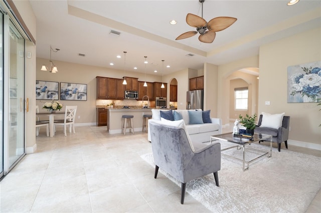 living room featuring arched walkways, recessed lighting, a raised ceiling, visible vents, and light tile patterned flooring