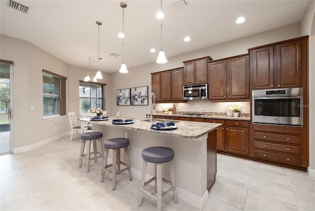 kitchen with appliances with stainless steel finishes, visible vents, a sink, and tasteful backsplash