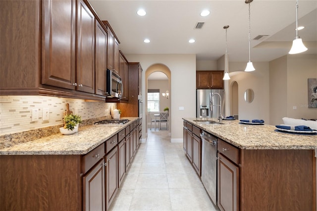 kitchen with arched walkways, tasteful backsplash, visible vents, appliances with stainless steel finishes, and a sink