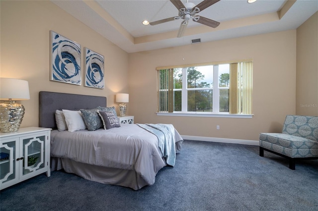 bedroom featuring a tray ceiling, recessed lighting, visible vents, dark carpet, and baseboards