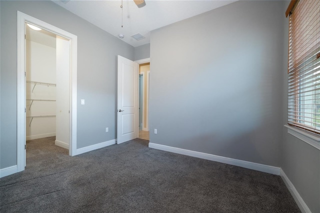 unfurnished bedroom featuring dark colored carpet, visible vents, and baseboards