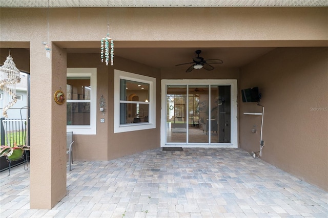 property entrance with a patio, fence, a ceiling fan, and stucco siding