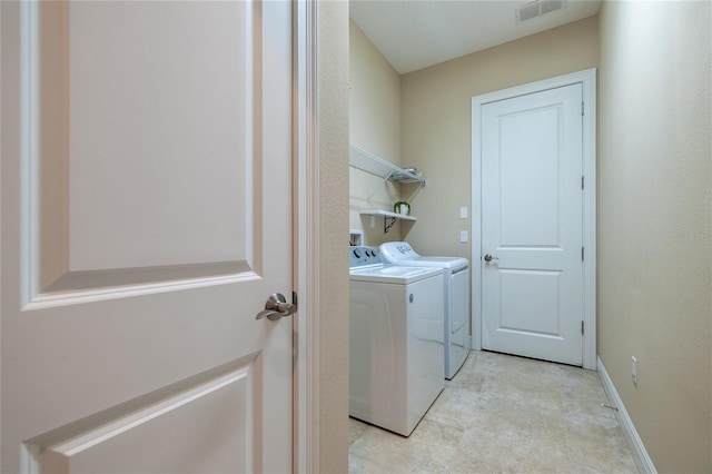 clothes washing area with laundry area, washing machine and clothes dryer, visible vents, and baseboards