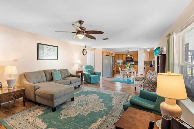 living room featuring a ceiling fan, light wood-type flooring, and visible vents