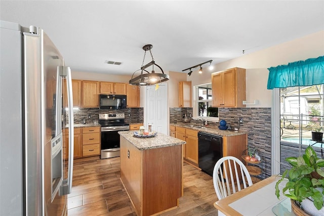 kitchen featuring black appliances, plenty of natural light, light wood-style flooring, and decorative backsplash