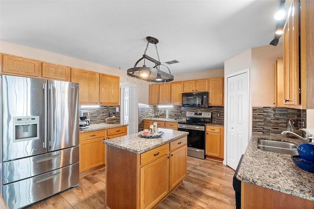 kitchen featuring a center island, visible vents, appliances with stainless steel finishes, light wood-style floors, and a sink