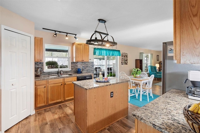 kitchen with light stone counters, a kitchen island, a sink, decorative backsplash, and light wood finished floors